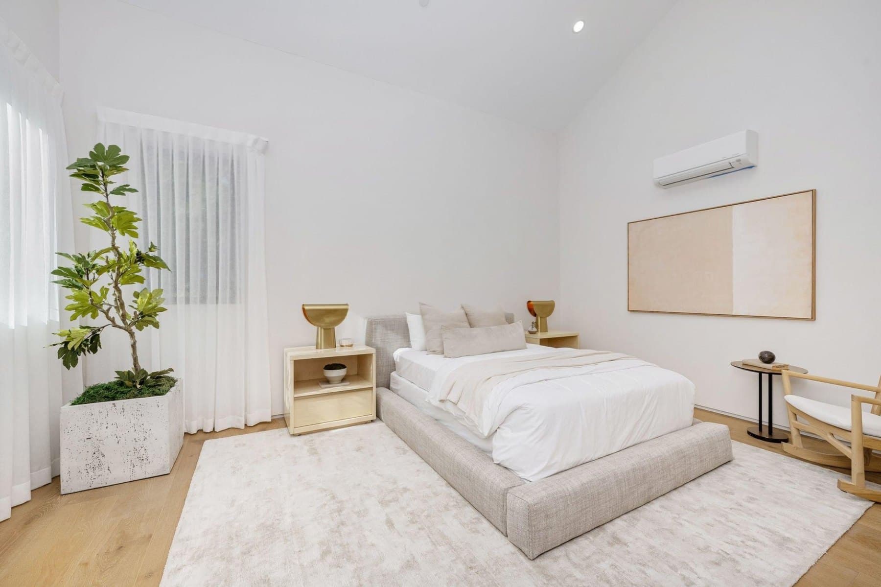 A serene, minimalist primary bedroom with a perfectly made bed