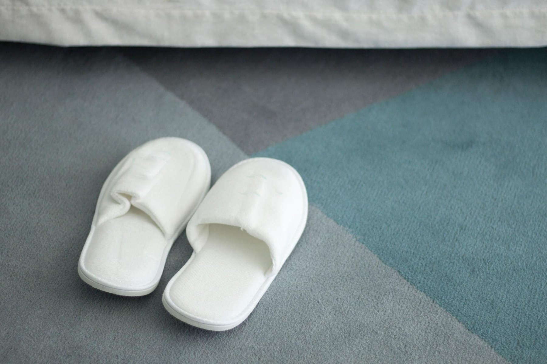 White slippers resting on a soft bedroom rug
